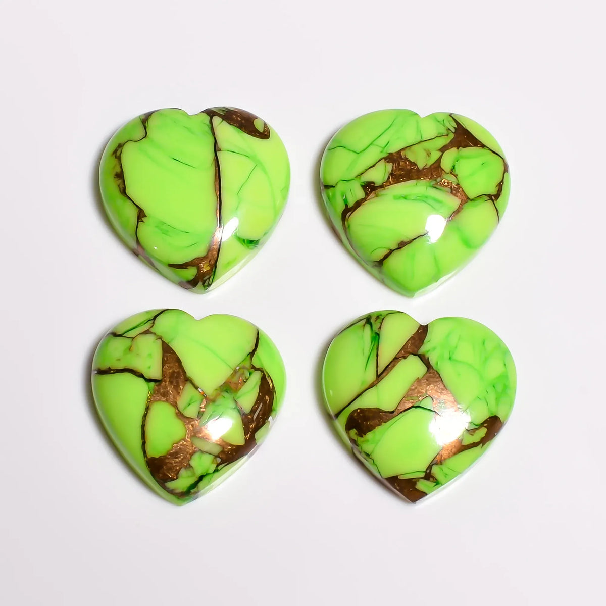 Polished green copper turquoise gemstone hearts in lime color, top-down view