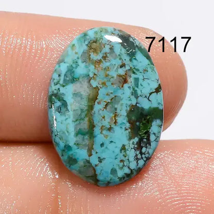 Turquoise stone held between fingers with a visible number '7117' on a white background
