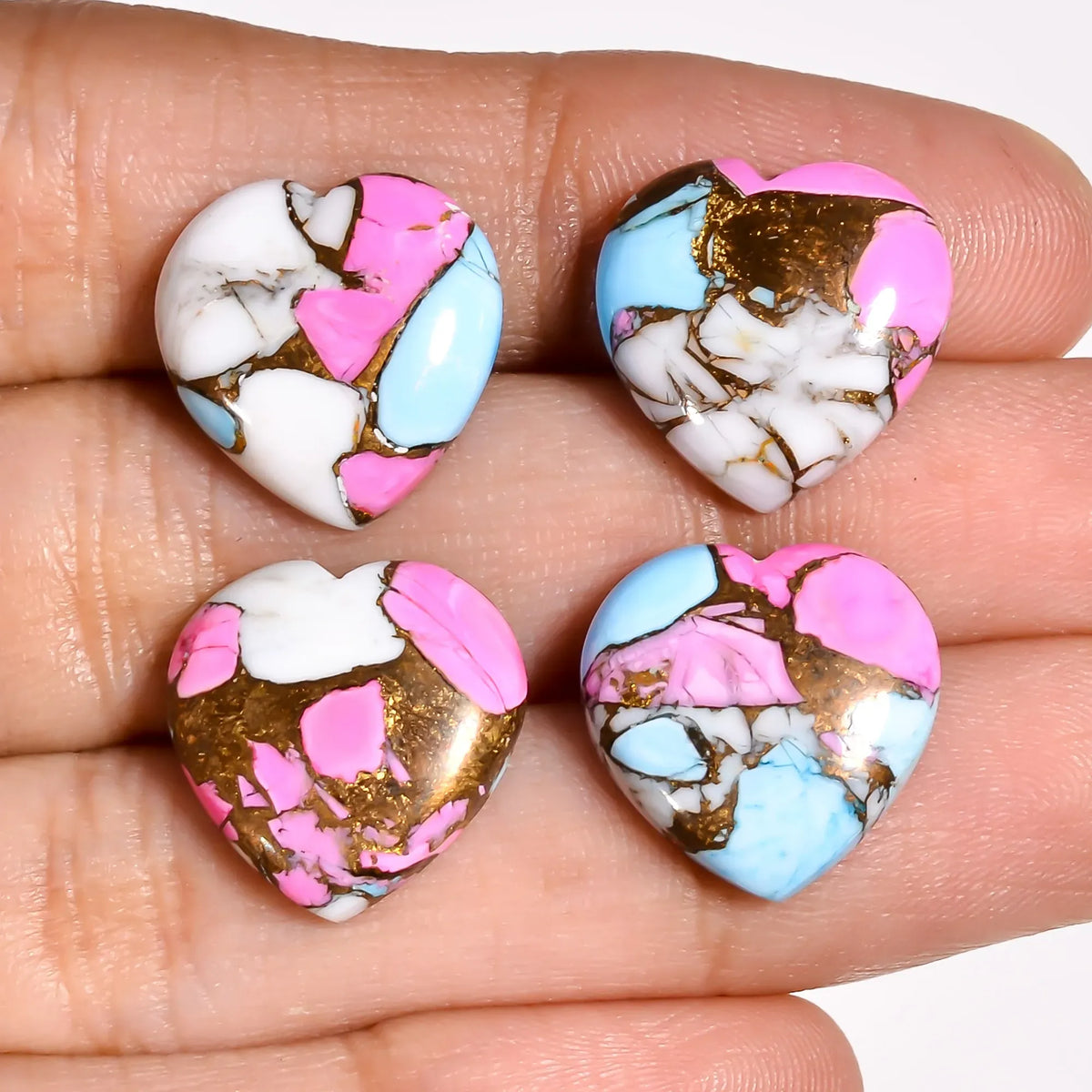 Four pink and white Mohave turquoise heart cabochons on a white background