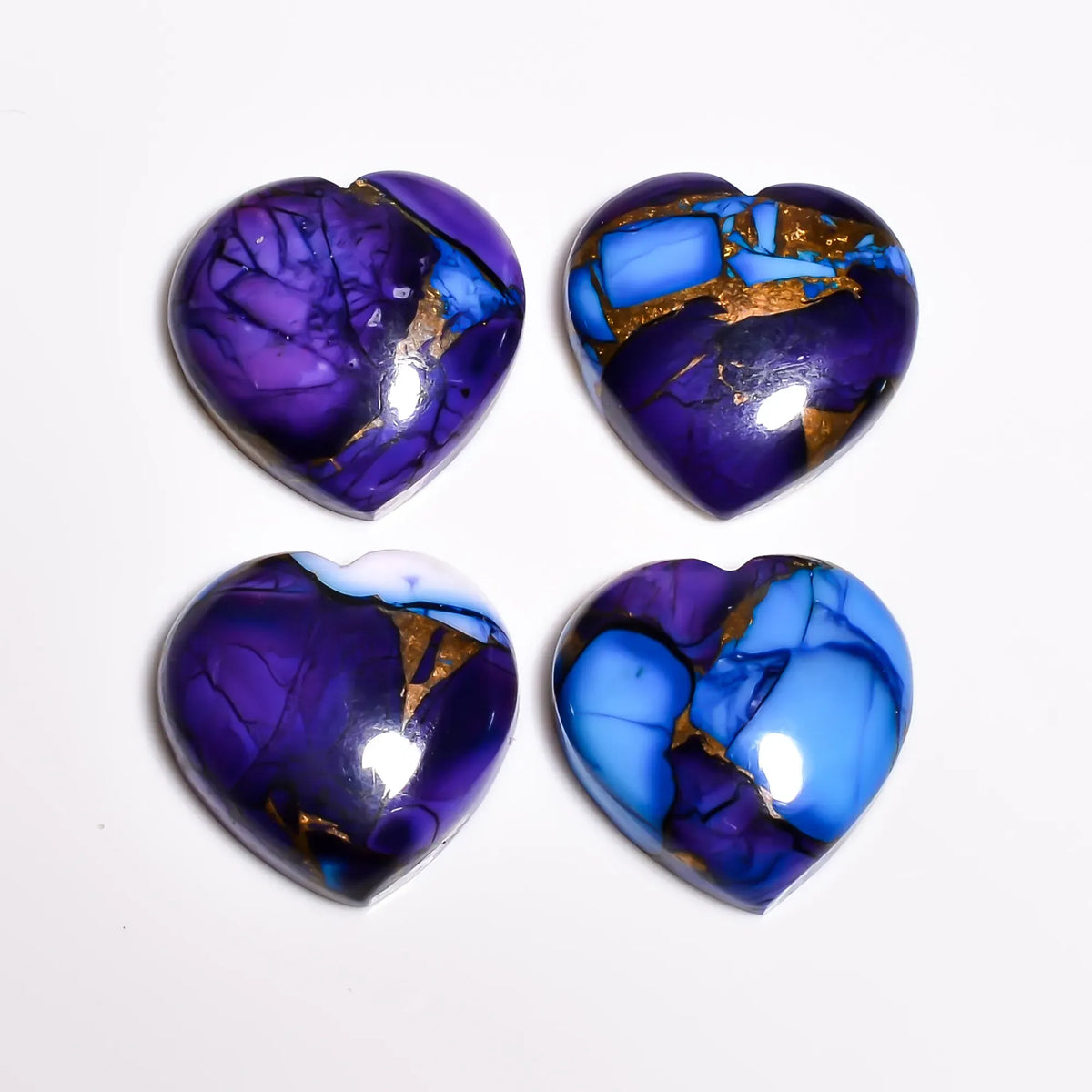 Purple and blue turquoise cabochon hearts showing copper turquoise matrix and glossy domes, top view