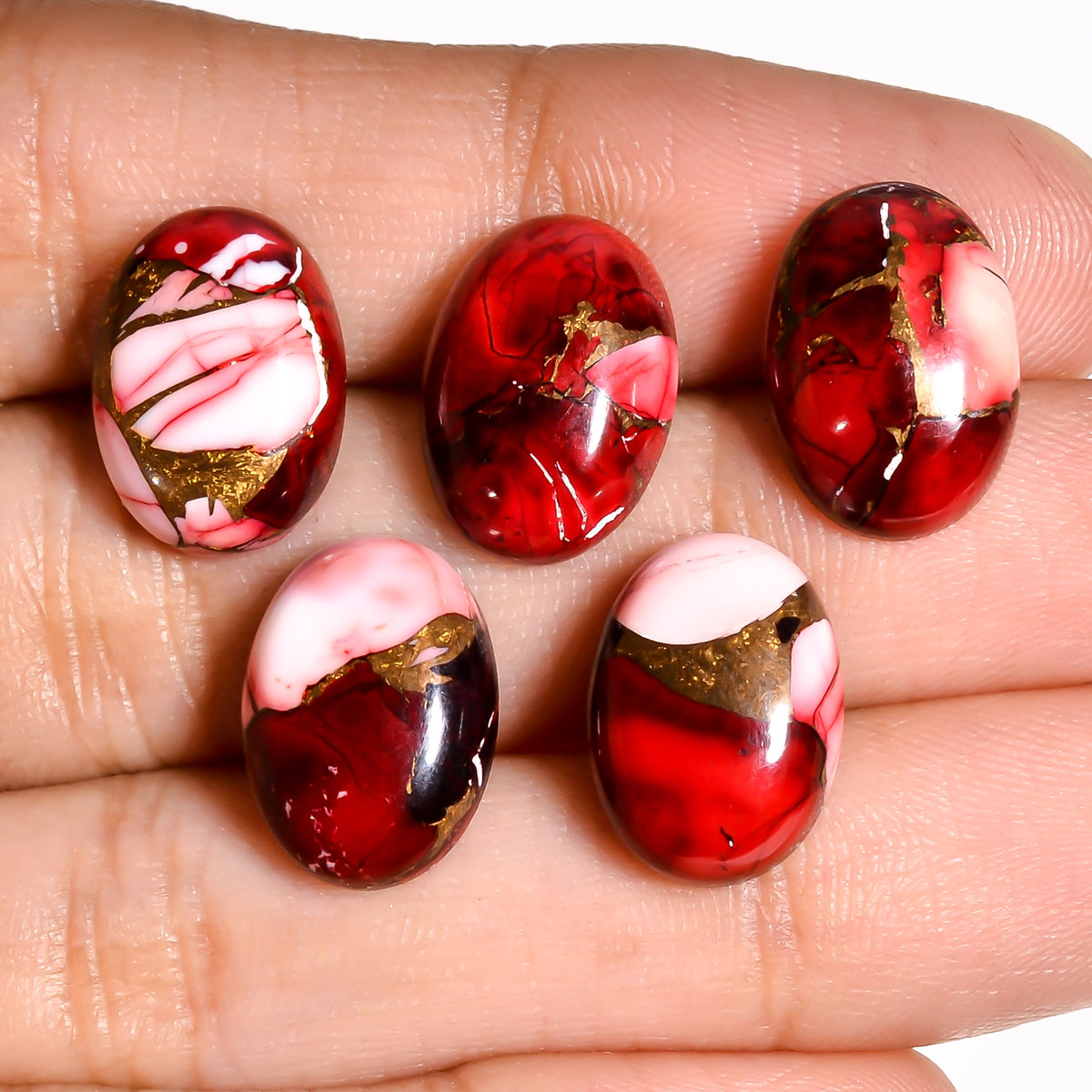 Red Turquoise oval cabochon held in hand for scale, giving buyers a realistic sense of the stone's actual size before ordering