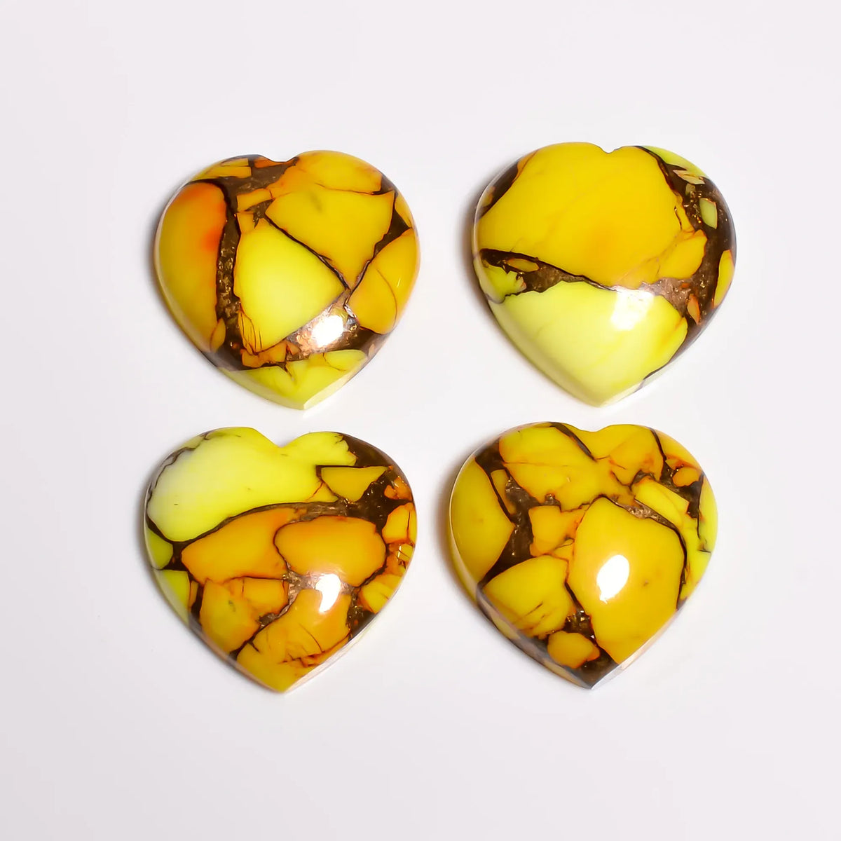 Polished yellow turquoise stone hearts, loose gemstones with glossy domed tops, top-down view